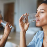 couple drinking glasses of water together at home