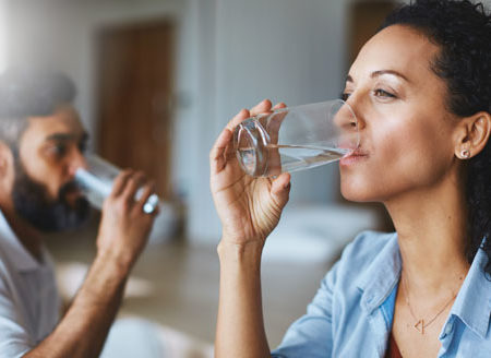 couple drinking glasses of water together at home